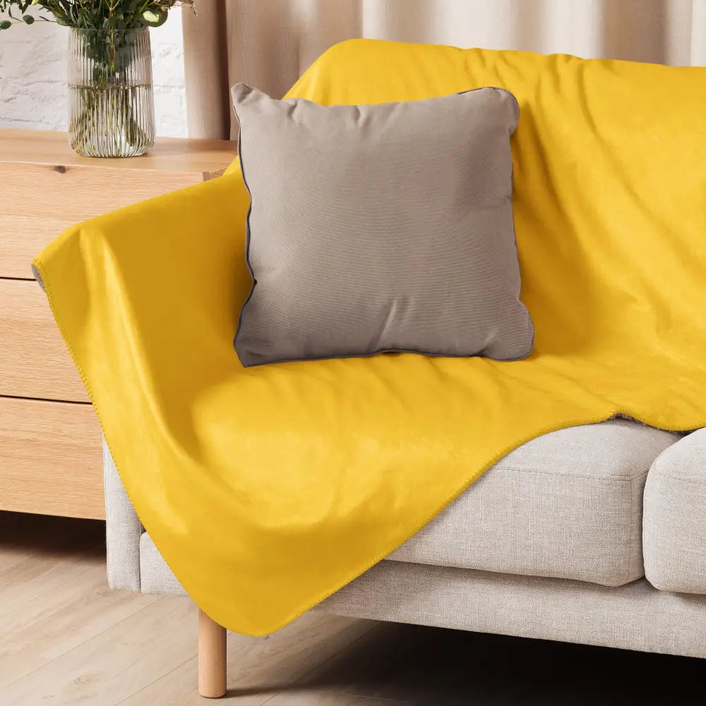 Bright yellow fleece mustard sherpa blanket draped over a sofa showing soft cozy texture and warmth