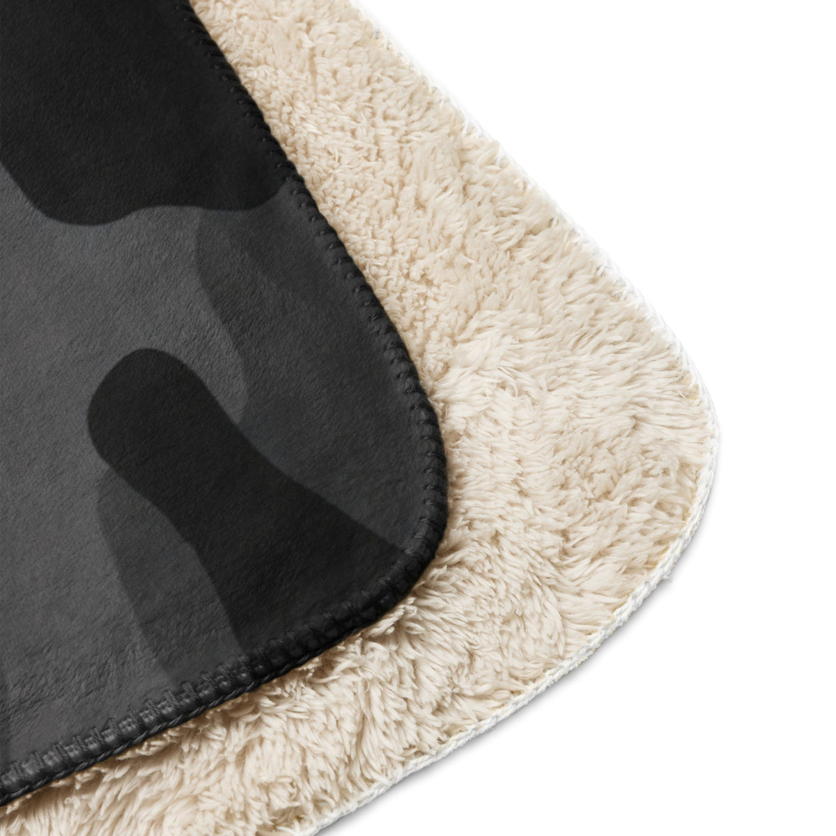 Cream-colored plush fleece blanket showing the black camouflage pattern on the reverse side of the black camo blanket