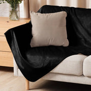 Black sherpa blanket with soft velvet texture draped over sofa showcasing cozy material and dark color