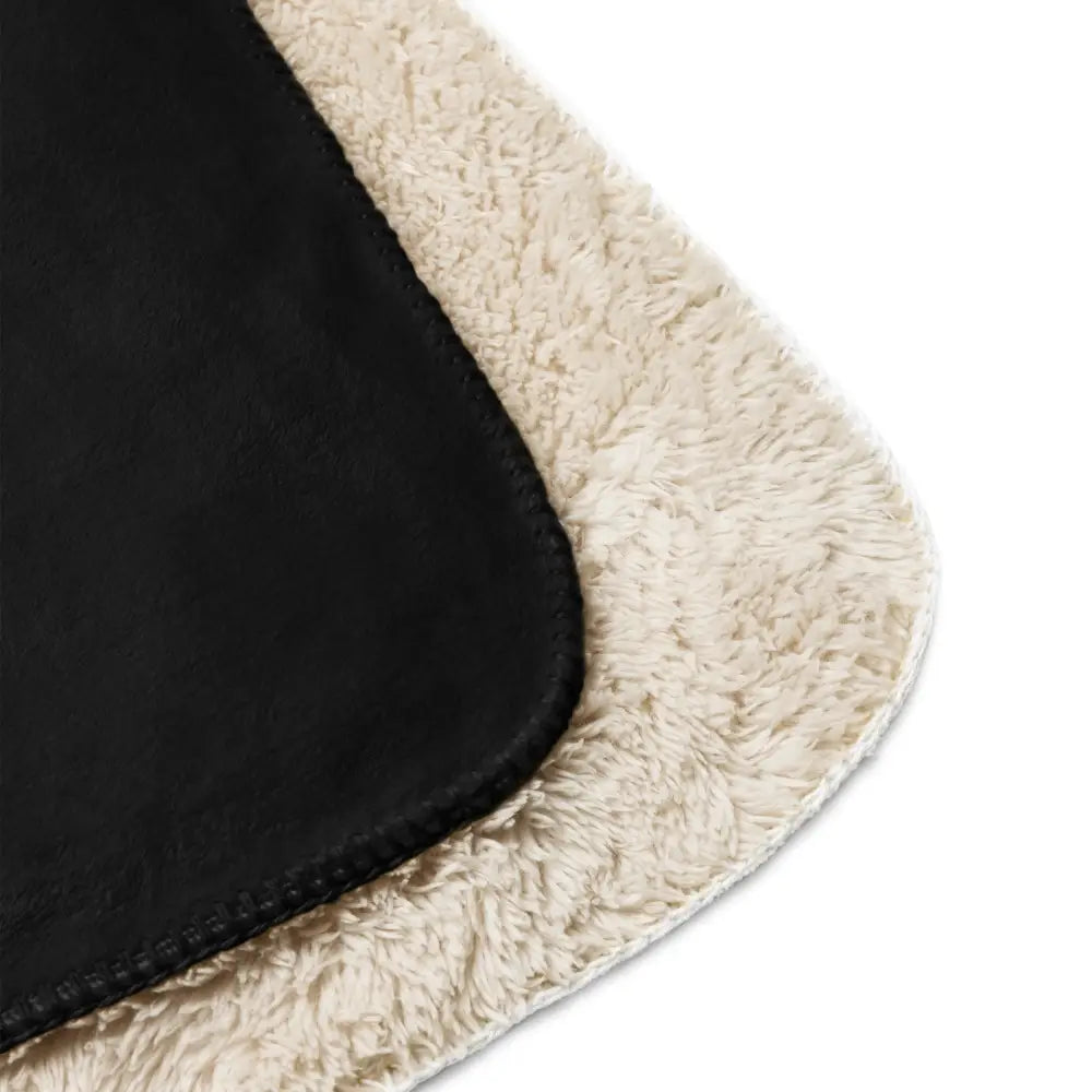 Black sherpa blanket featuring black and cream shearling with a plush textured outer layer and smooth stitched edge