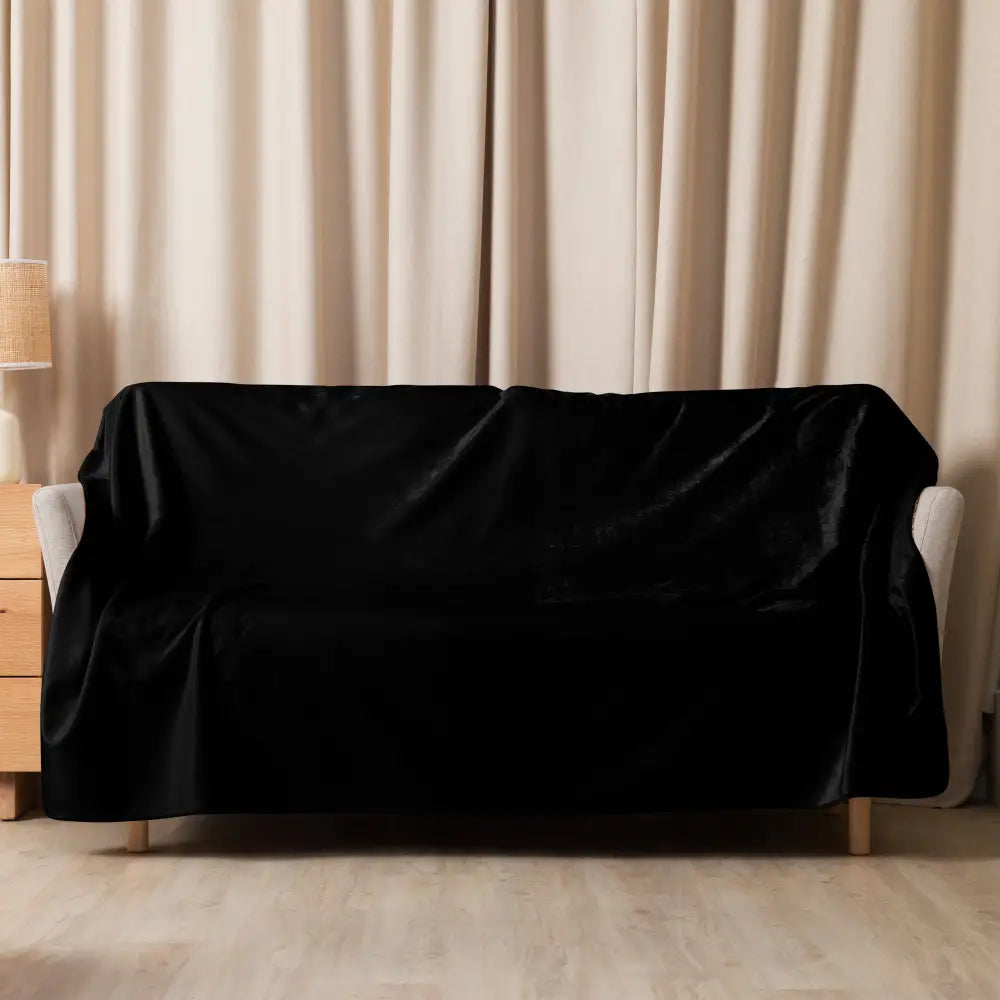 Black sherpa blanket draped over a black velvet sofa cover showcasing soft texture and cozy warmth