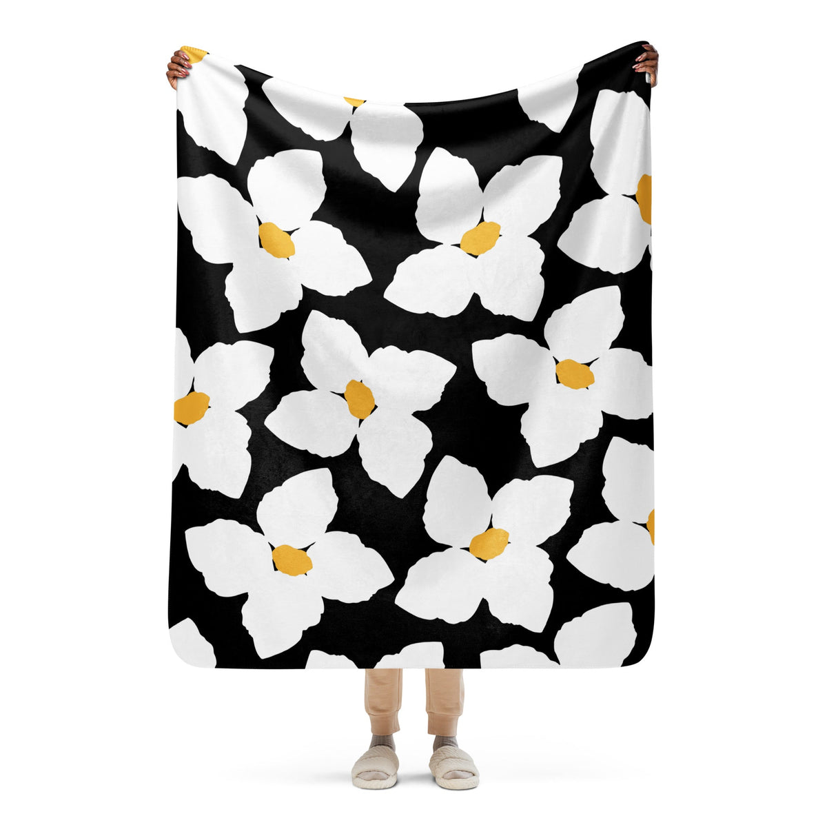 A soft black and white floral blanket with bold white flowers and yellow centers perfect for cozy use
