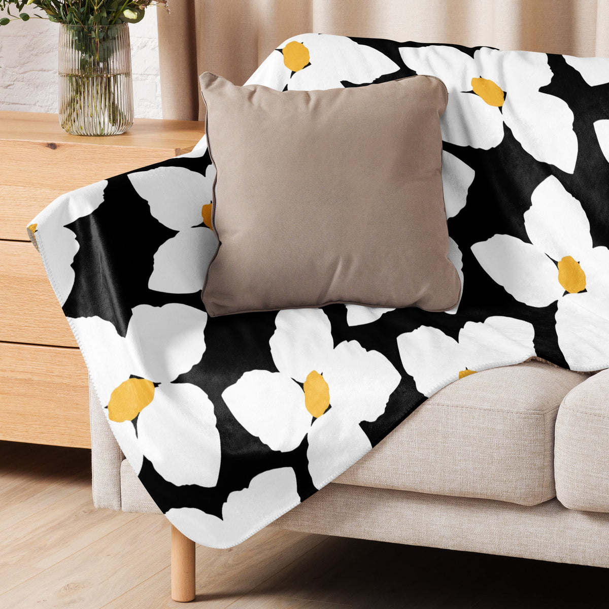 Black and white floral blanket with yellow pattern draped over beige sofa showcasing soft cozy fabric texture