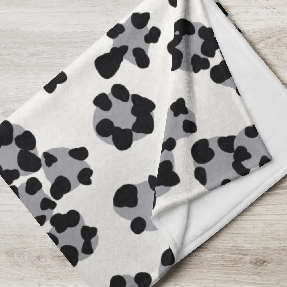 A soft white black and white leopard print blanket with bold black and gray paw print pattern