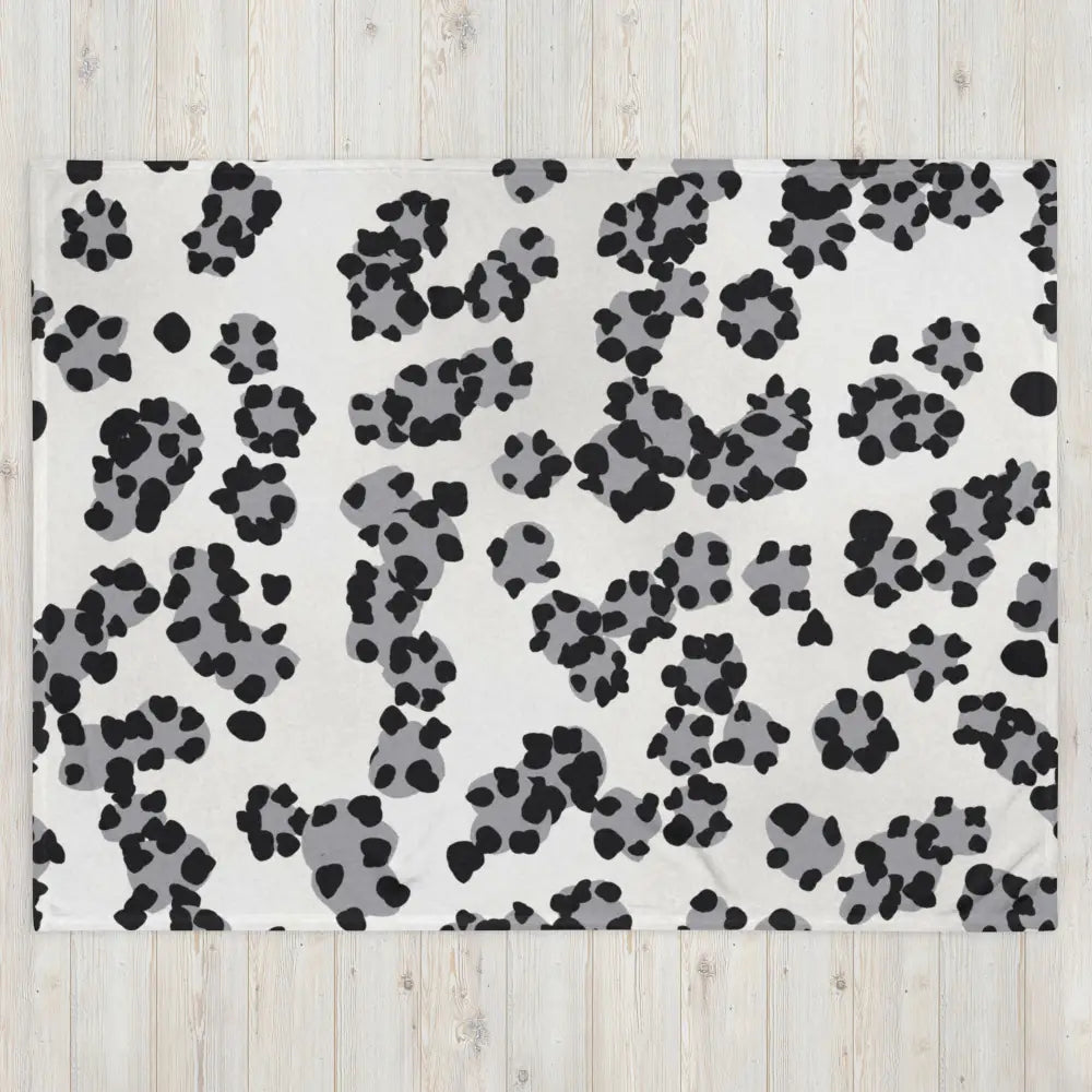 A white fleece black and white leopard print blanket with playful black and gray paw prints pattern