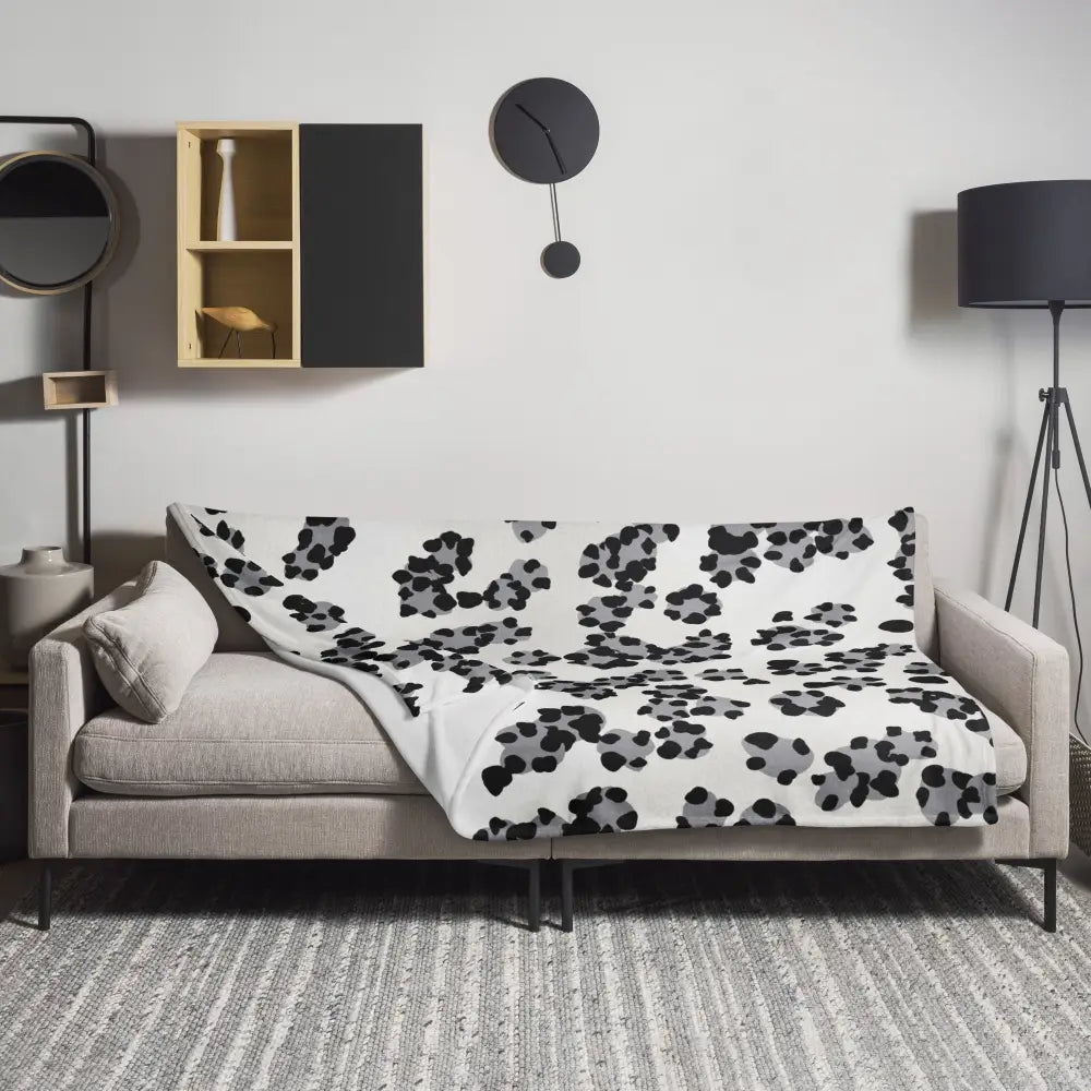 A cozy black and white leopard print blanket draped over a modern beige sofa with bold gray accents