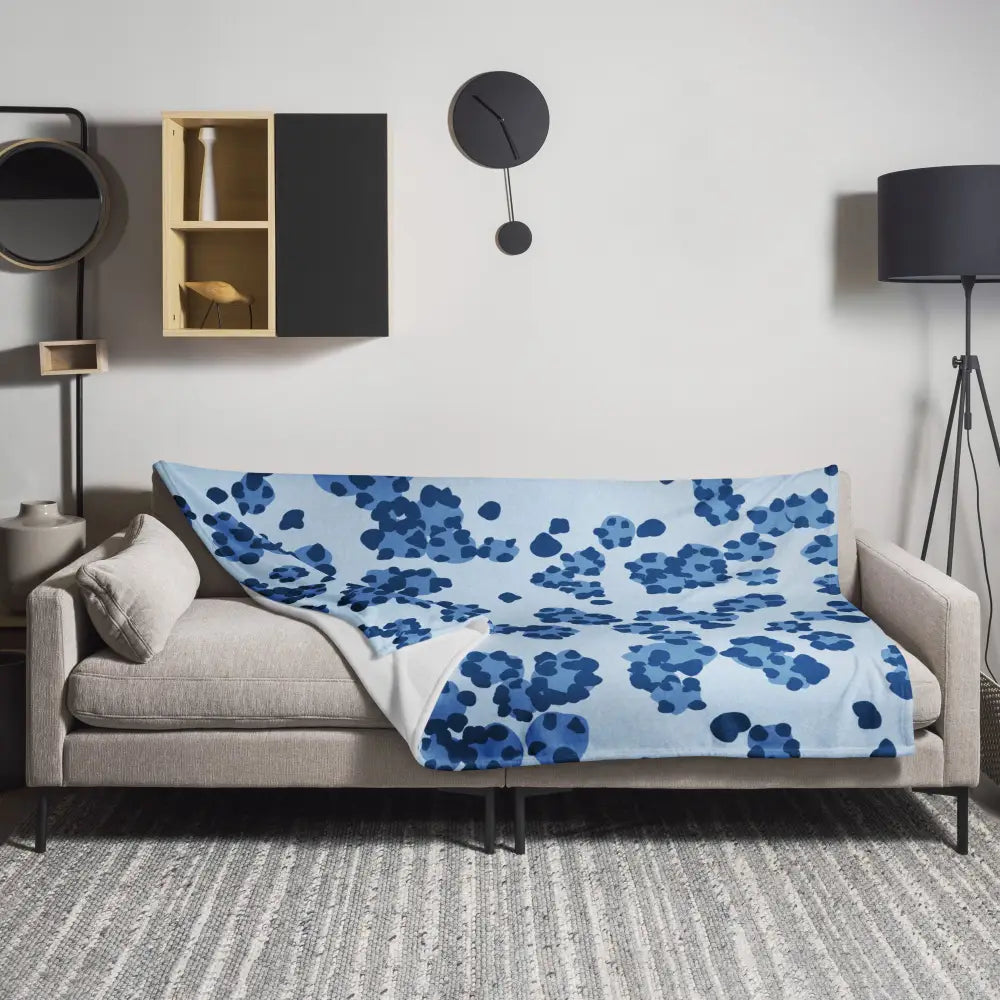 Une couverture bleue leopard en tissu doux avec un motif floral abstrait bleu marine sur un canapé beige moderne