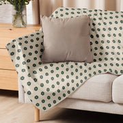A soft cream-colored boho floral blanket with dark green floral motifs perfect for cozy home decor