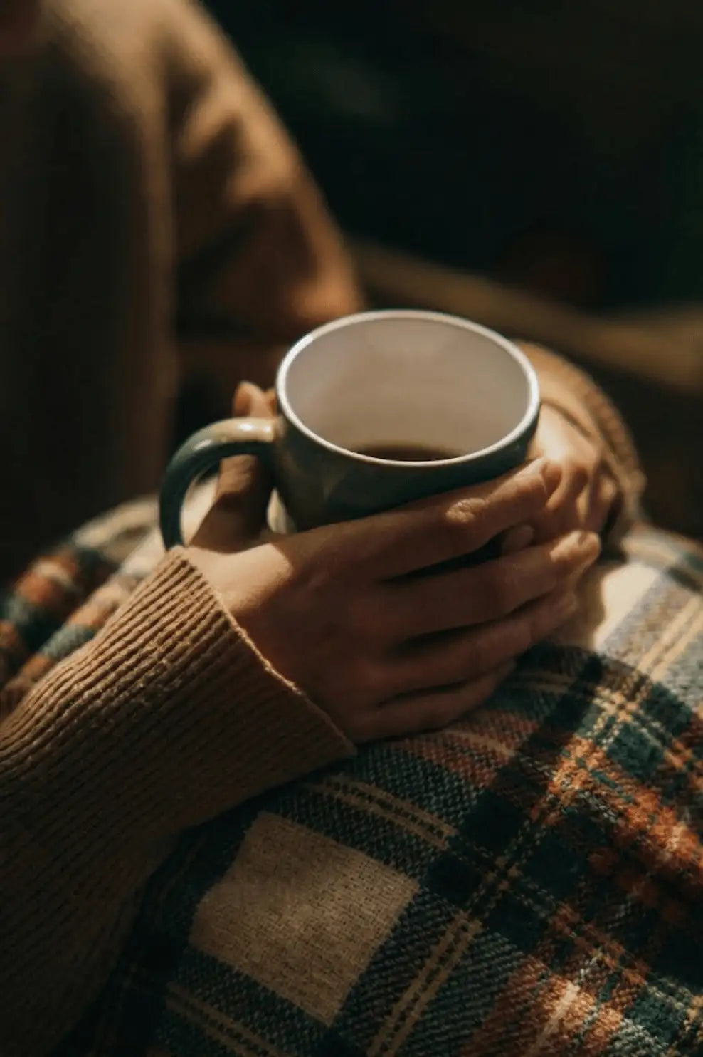 A ceramic mug with a dark green handle and rim, holding a warm beverage.