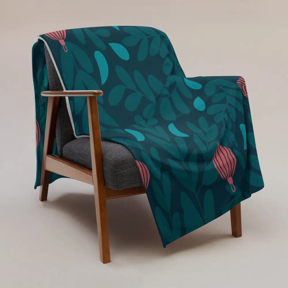 Teal and pink hot air balloon patterned Christmas ornament throw blanket draped over a wooden armchair