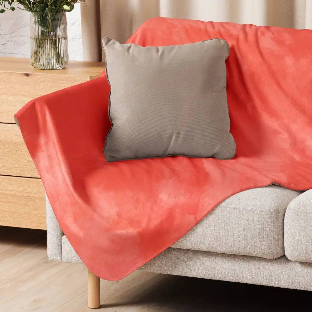 Coral sherpa blanket soft coral-colored fleece blanket draped over sofa with gray pillow