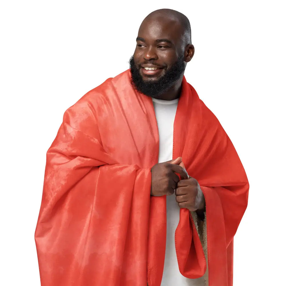 A vibrant red coral sherpa blanket draped over a man’s shoulders with soft folds and a plush cozy texture