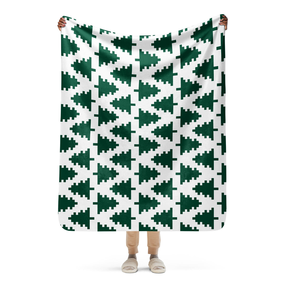 A soft white Christmas blanket made of cozy material with dark green pixelated Christmas tree patterns