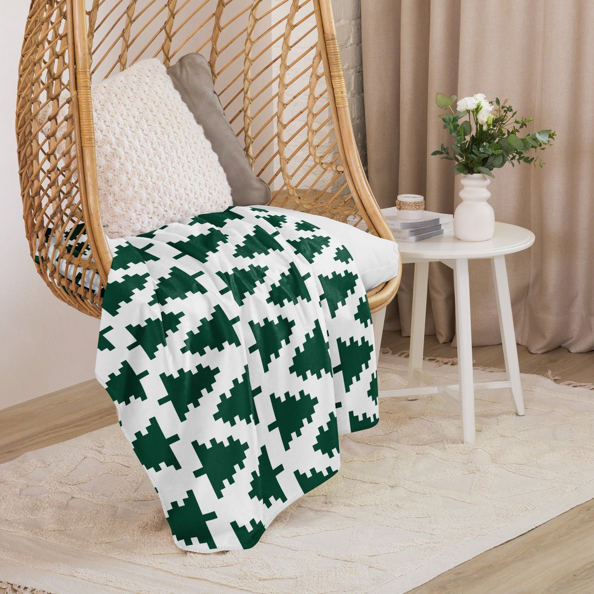 A cozy white throw blanket with a repeating pattern of dark green pixelated christmas trees for holiday decor