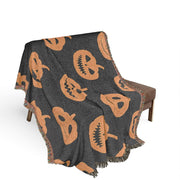 Black woven Halloween blanket with orange pumpkin faces and fringed edges perfect for festive decor