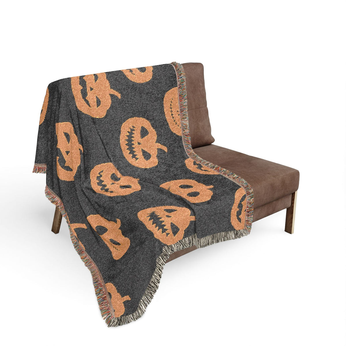 Halloween woven blanket in dark gray with orange pumpkin faces and fringed edges for festive decor