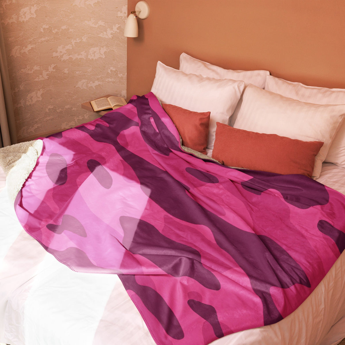 A vibrant hot pink camo blanket with purple camouflage pattern draped over a bed for cozy use