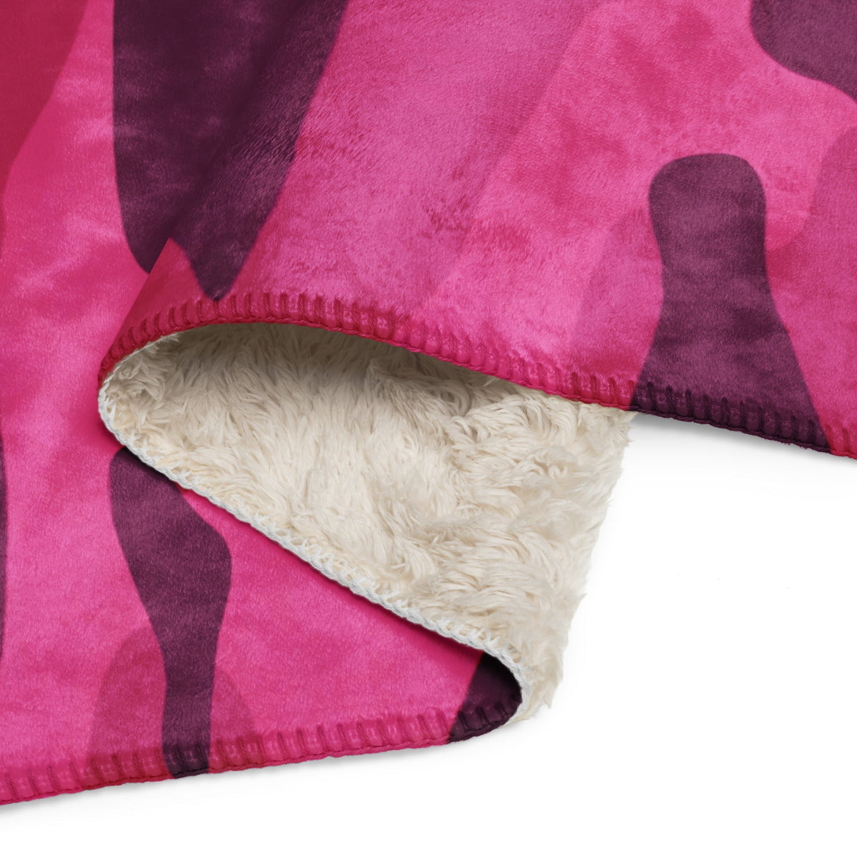 A hot pink camo blanket with vibrant pink and purple camouflage and a soft white sherpa lining for cozy warmth