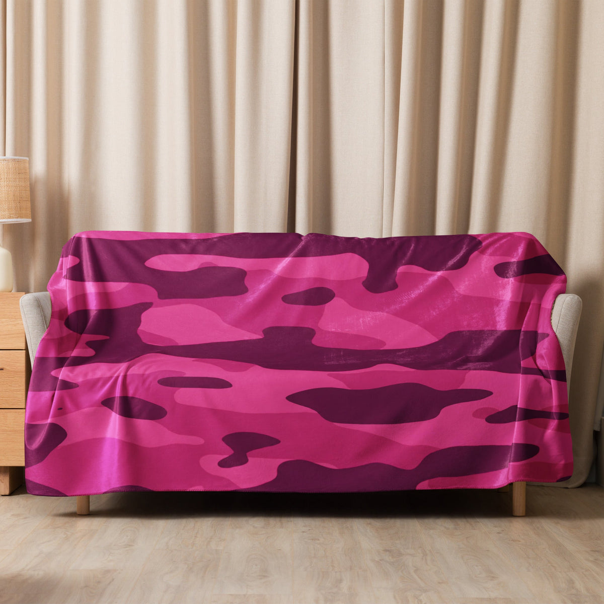 A vibrant hot pink camo blanket with purple camouflage pattern draped over a sofa for cozy home use