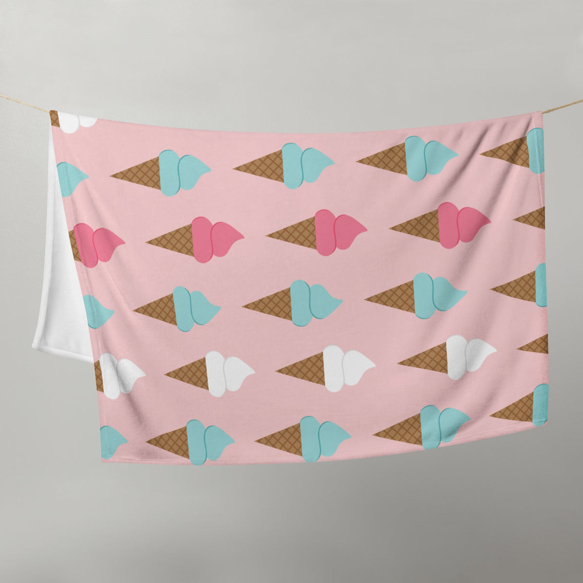 Pink blanket with repeating teal pink and white ice cream cone pattern on a soft pastel background for cozy use