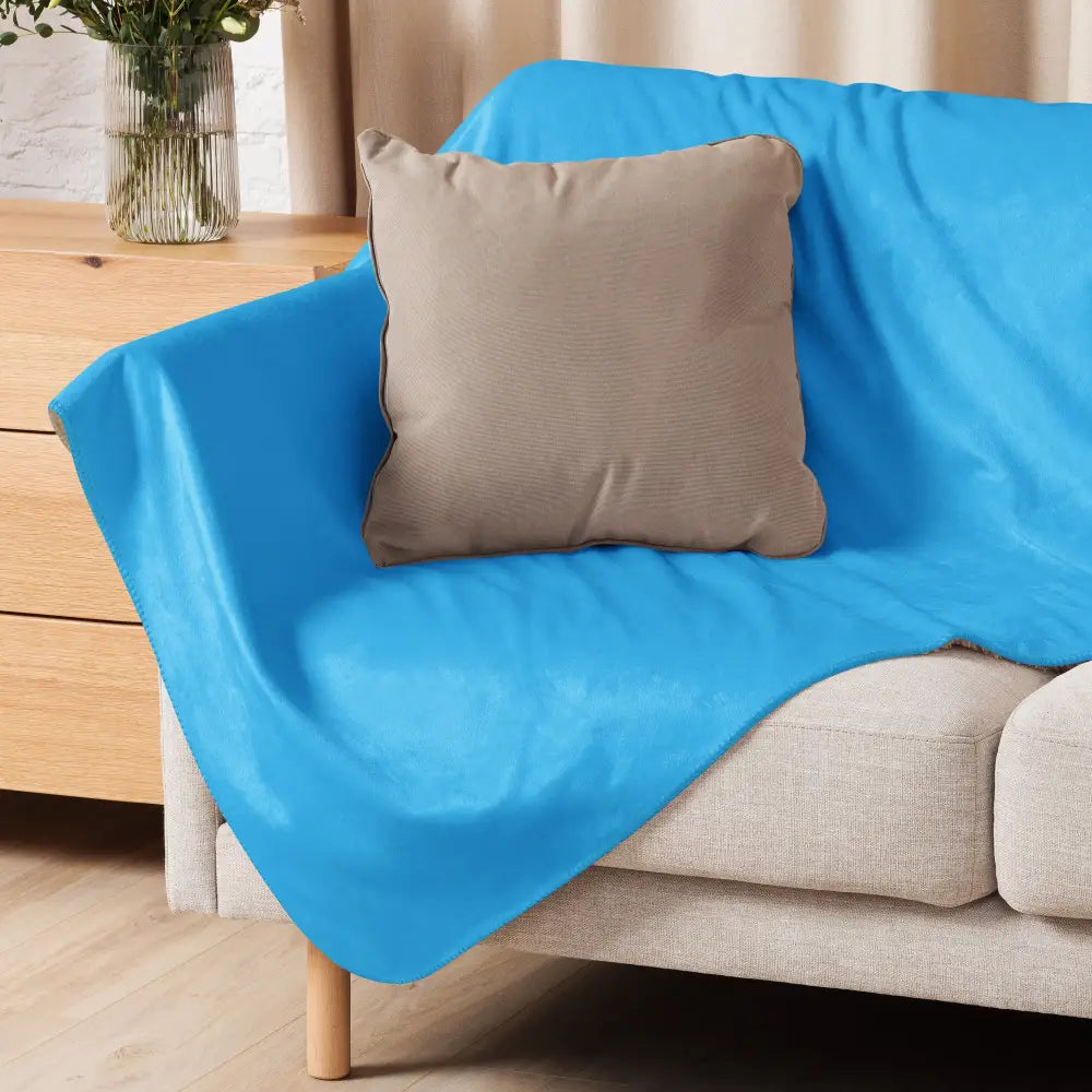 Light blue sherpa blanket plush and soft draped over a beige sofa for cozy warmth and comfort