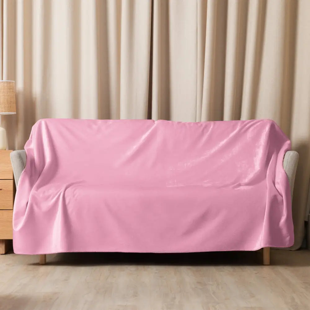 Light pink sherpa blanket draped over a pink velvet sofa showcasing soft cozy texture and elegant design
