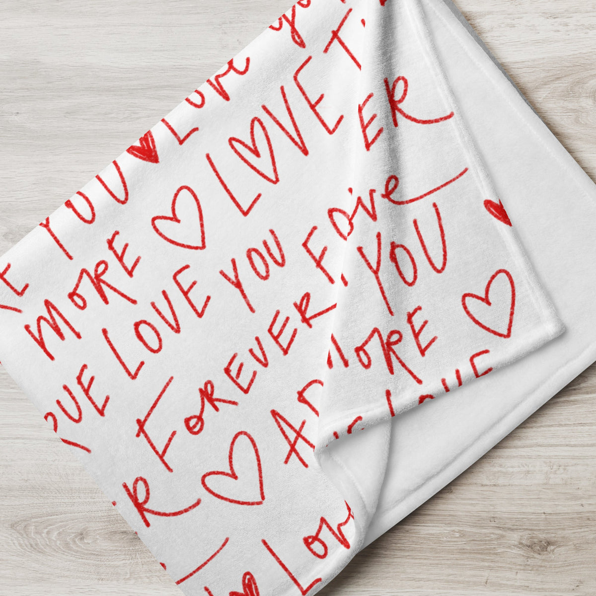 White love letter blanket with red handwritten style text and hearts reading i love you more and forever and ever