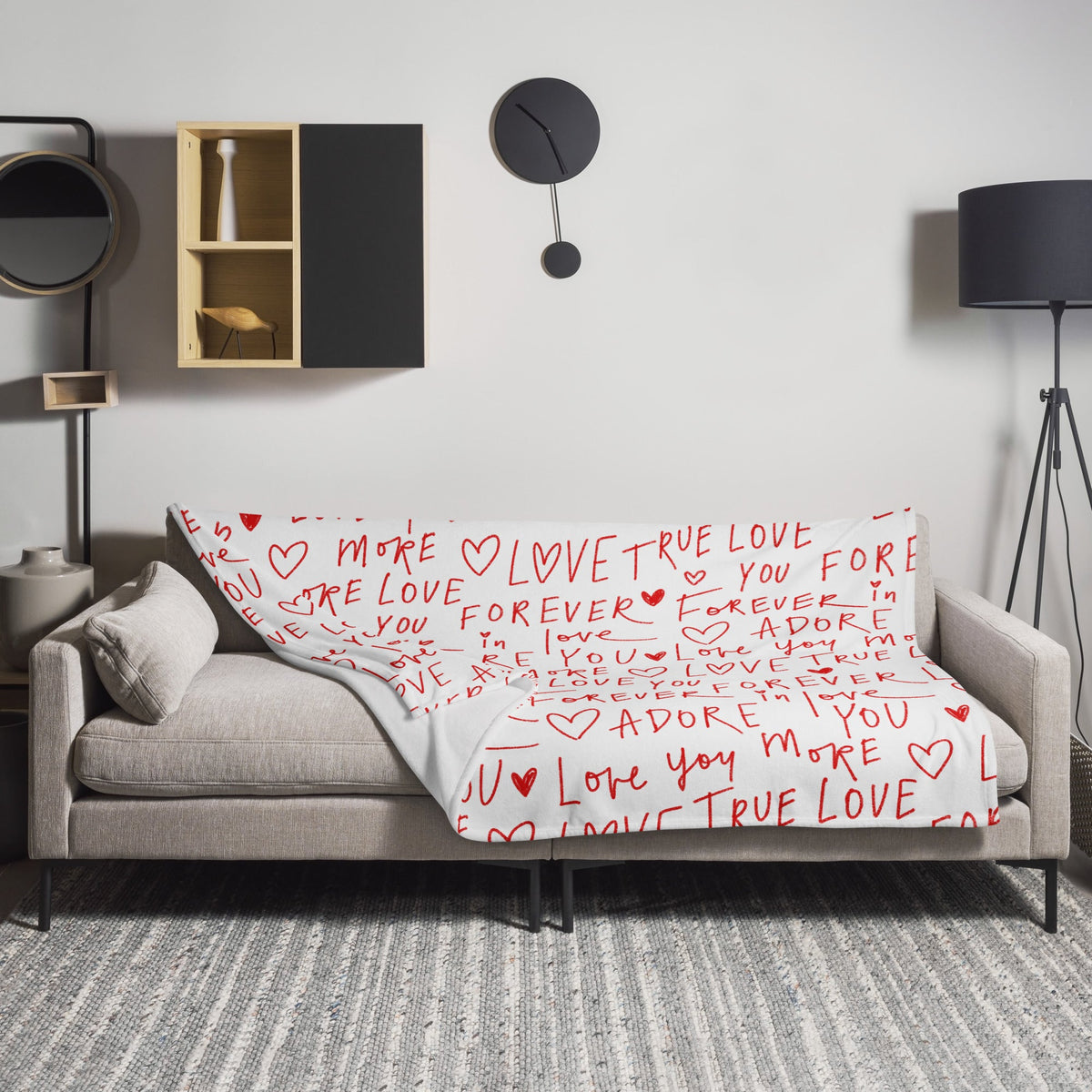 White love letter blanket with red handwritten-style love messages and hearts draped over a gray sofa