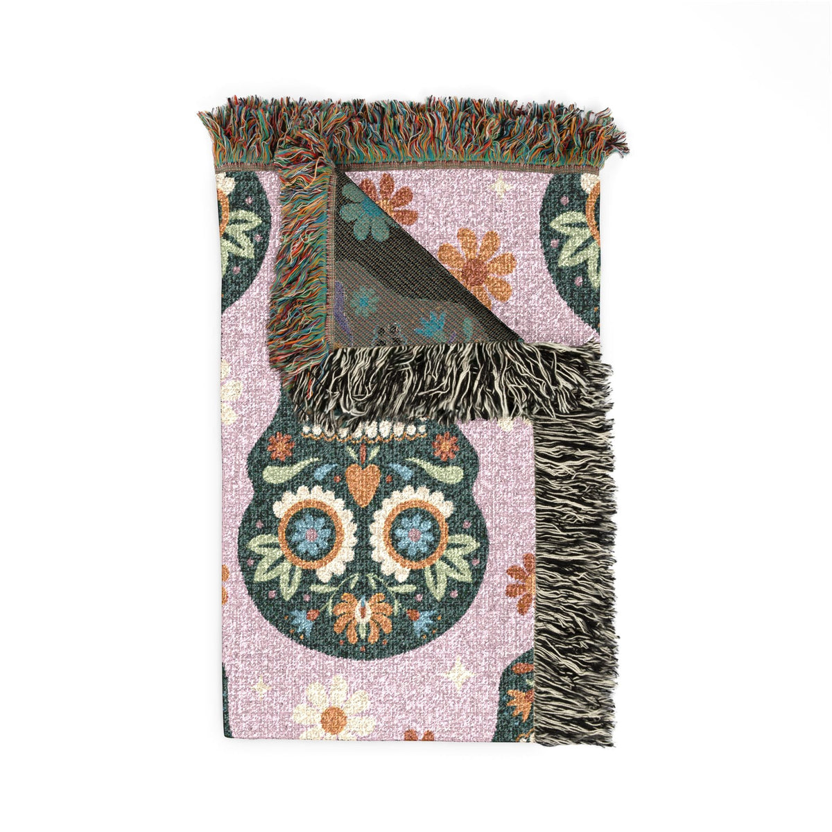 A soft pink Mexican woven blanket with a vibrant sugar skull floral design and multicolored fringe edges