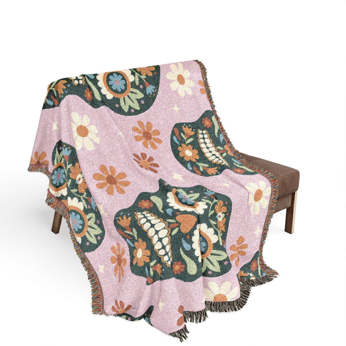A soft pink mexican woven blanket with vibrant floral botanical pattern and fringed edges