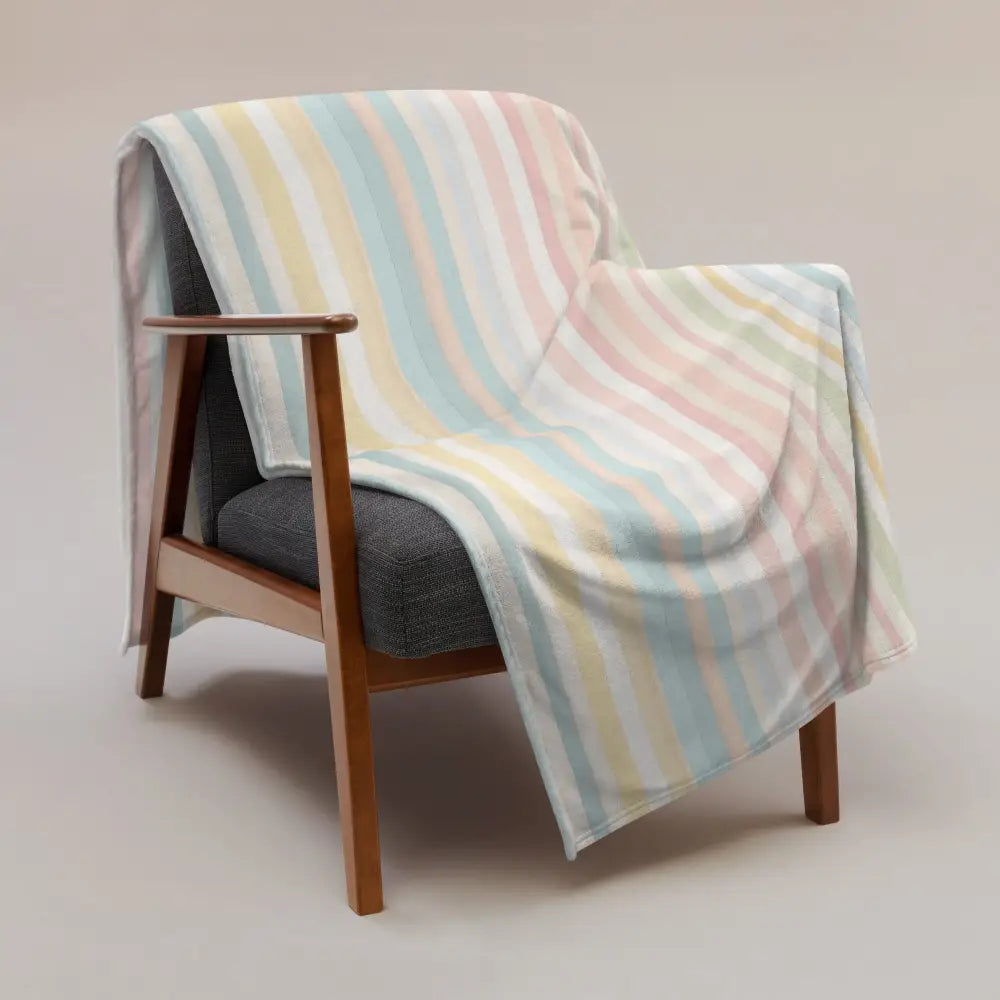 Couverture à rayures pastel multicolore en tissu doux drapée sur un fauteuil en bois