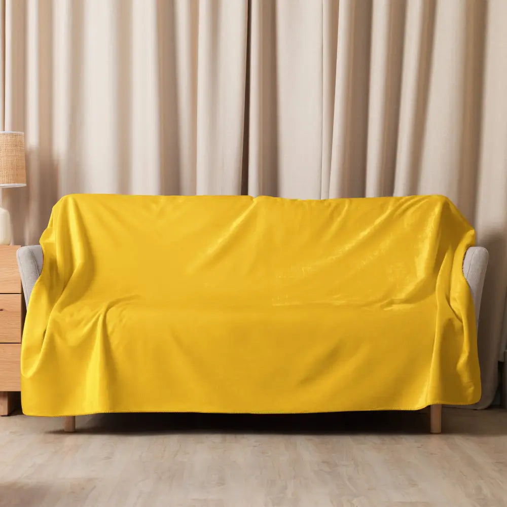 Bright yellow mustard sherpa blanket draped over a modern gray couch showcasing its plush soft texture