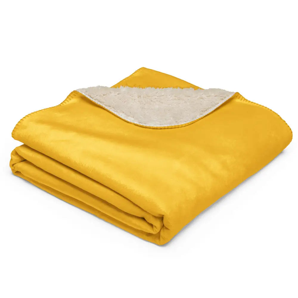 A folded mustard sherpa blanket featuring a plush white fleece lining for cozy warmth and softness