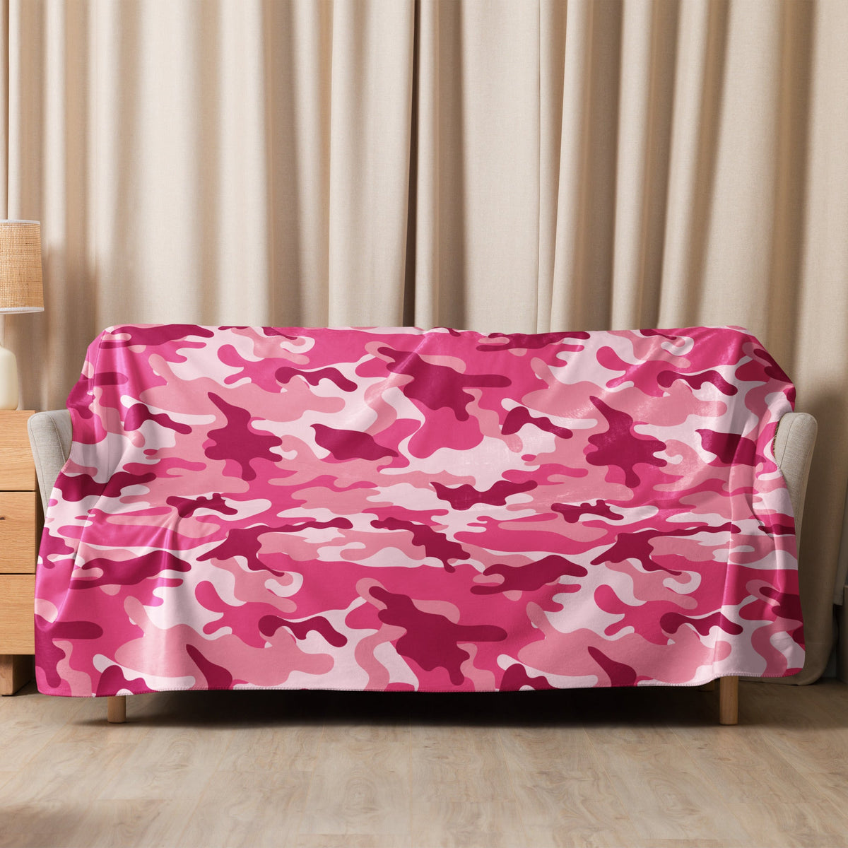A soft pink camo blanket with a camouflage pattern draped over a sofa for cozy home use