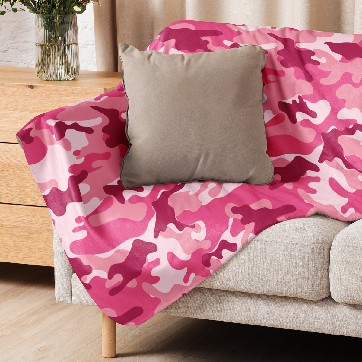 A soft pink camo blanket with camouflage pattern draped over a sofa for cozy home use