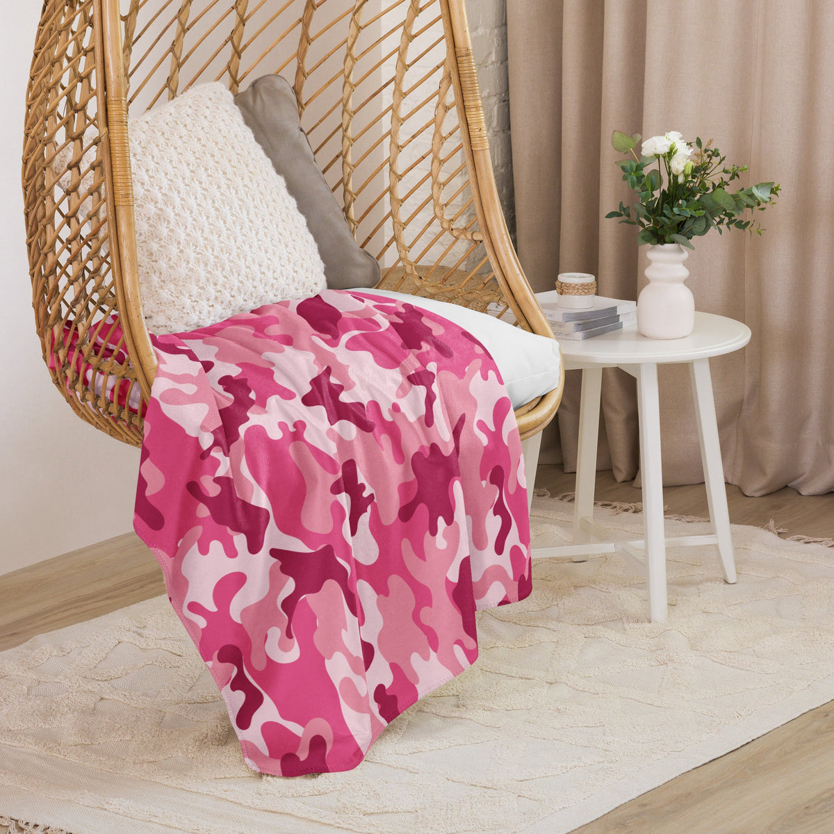 A soft pink and magenta camouflage patterned blanket draped over a wicker hanging chair for cozy use