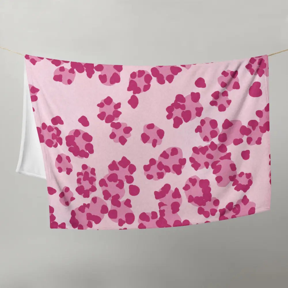 Une couverture rose douce avec un motif ludique d’empreintes de pattes rose foncé dispersées sur sa surface