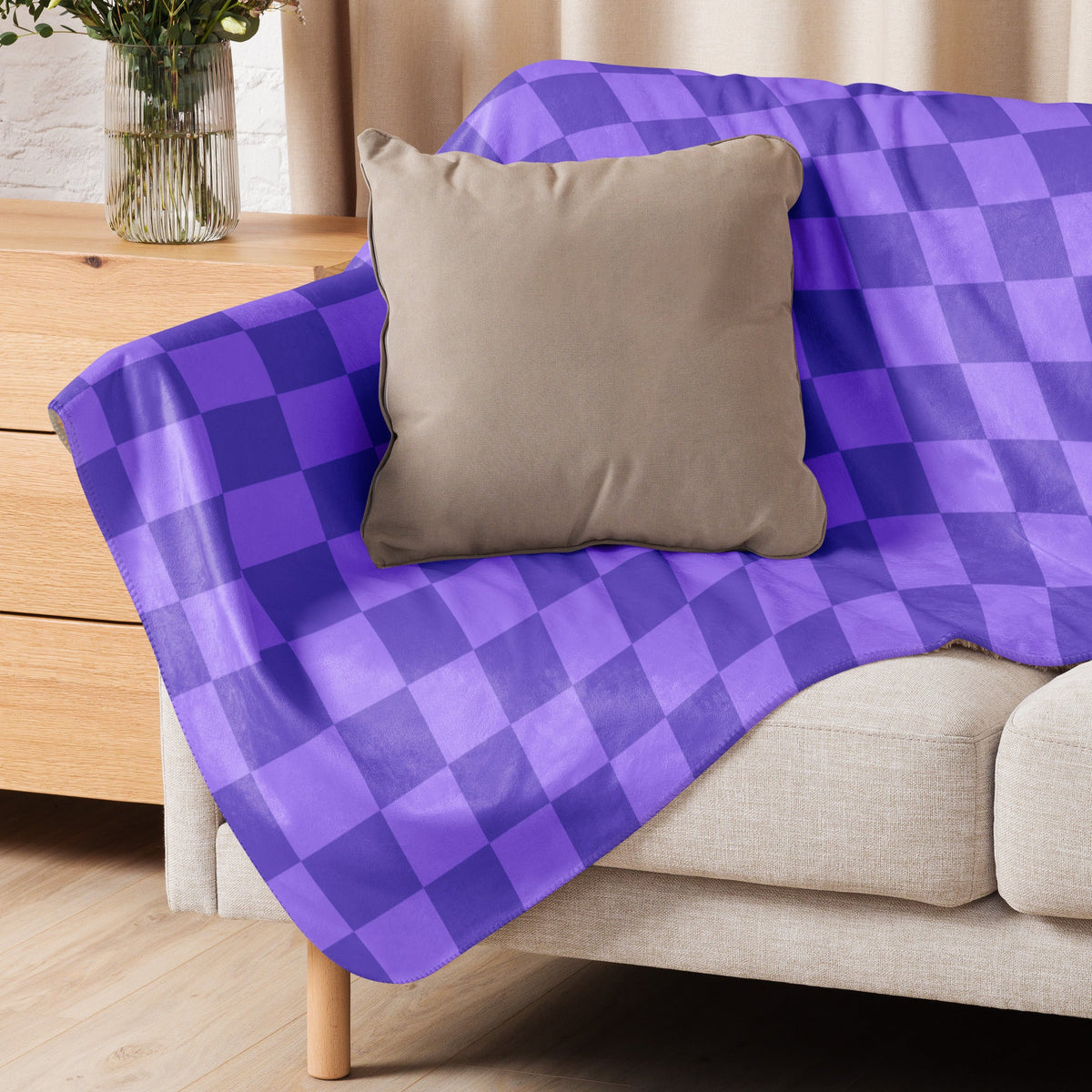 Purple checkered blanket in purple and navy blue draped over a beige sofa showcasing its soft fabric texture