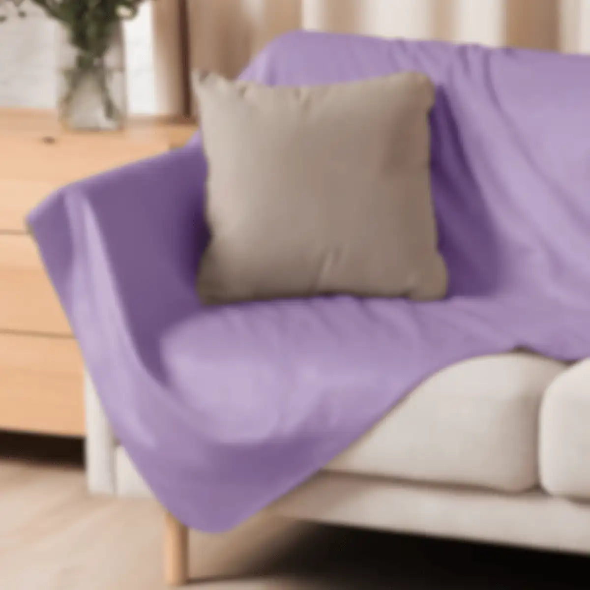 Purple fabric sofa cover draped over a beige couch with a matching pillow.