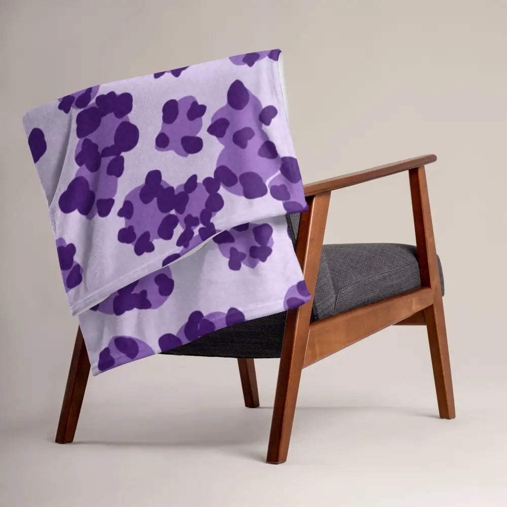 A soft lavender purple leopard print blanket with an abstract pattern draped over a wooden armchair