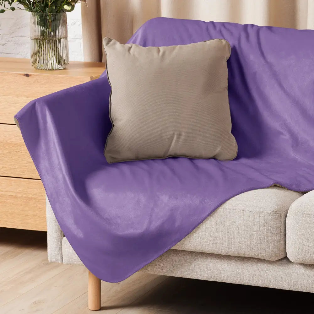 Purple sherpa throw blanket made of plush material draped over a sofa for cozy warmth and comfort