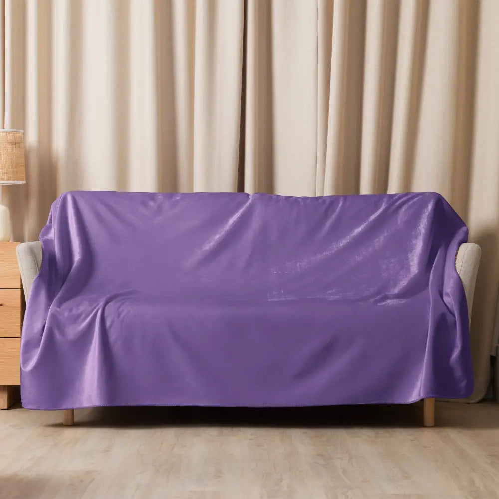 Purple sherpa throw blanket displayed on a purple velvet sofa cover highlighting softness and color contrast