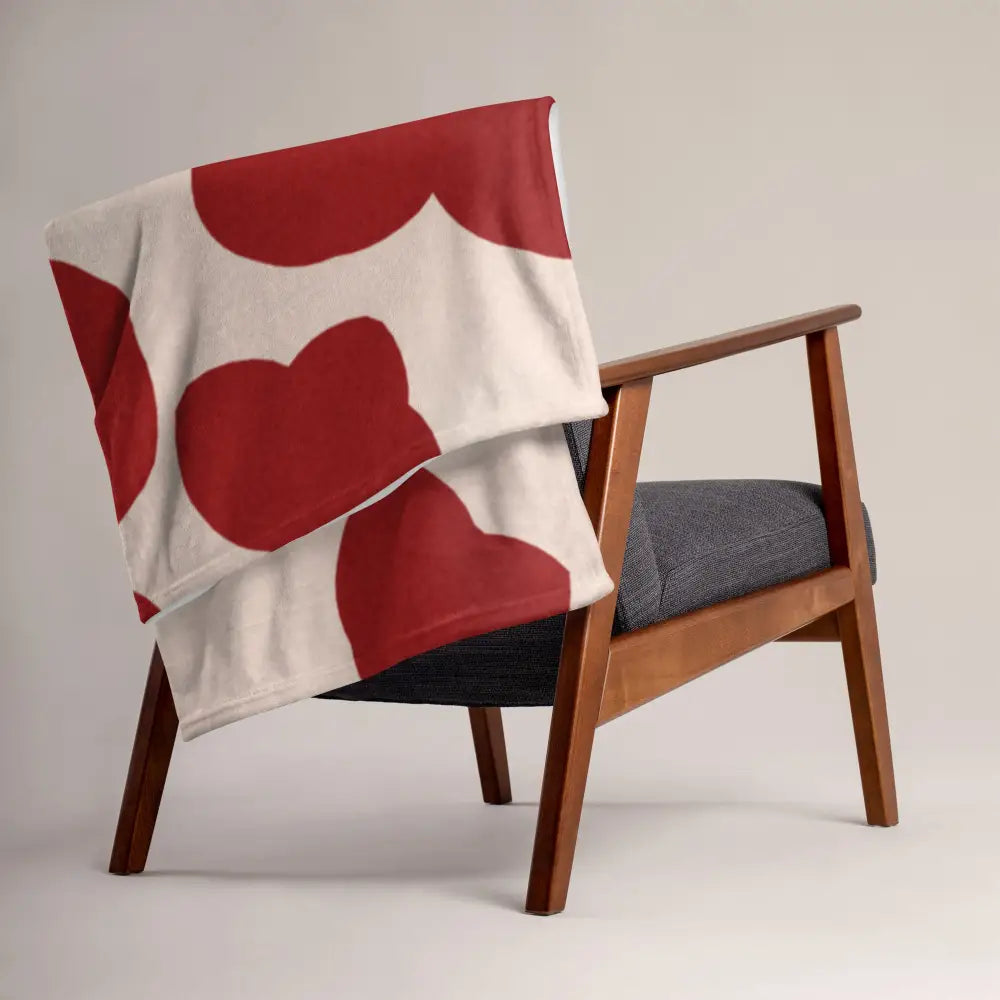 Plaid rouge et crème en tissu doux blanc avec motifs de cœurs rouges sur fauteuil en bois