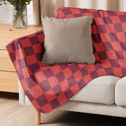 Red checkered blanket in red and maroon plaid draped over a beige sofa for cozy home use