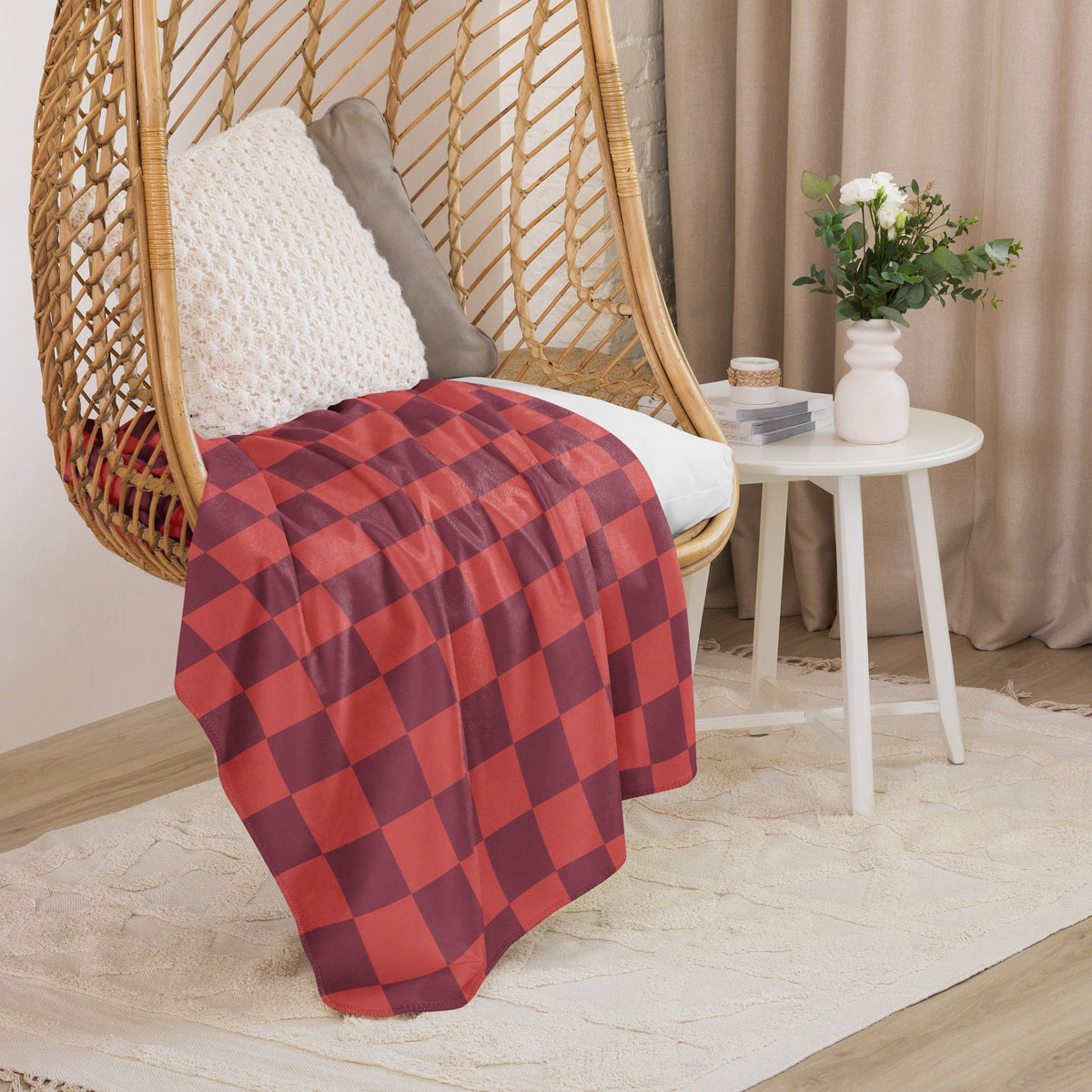 Red checkered blanket in red and maroon plaid draped over a wicker hanging chair for cozy use