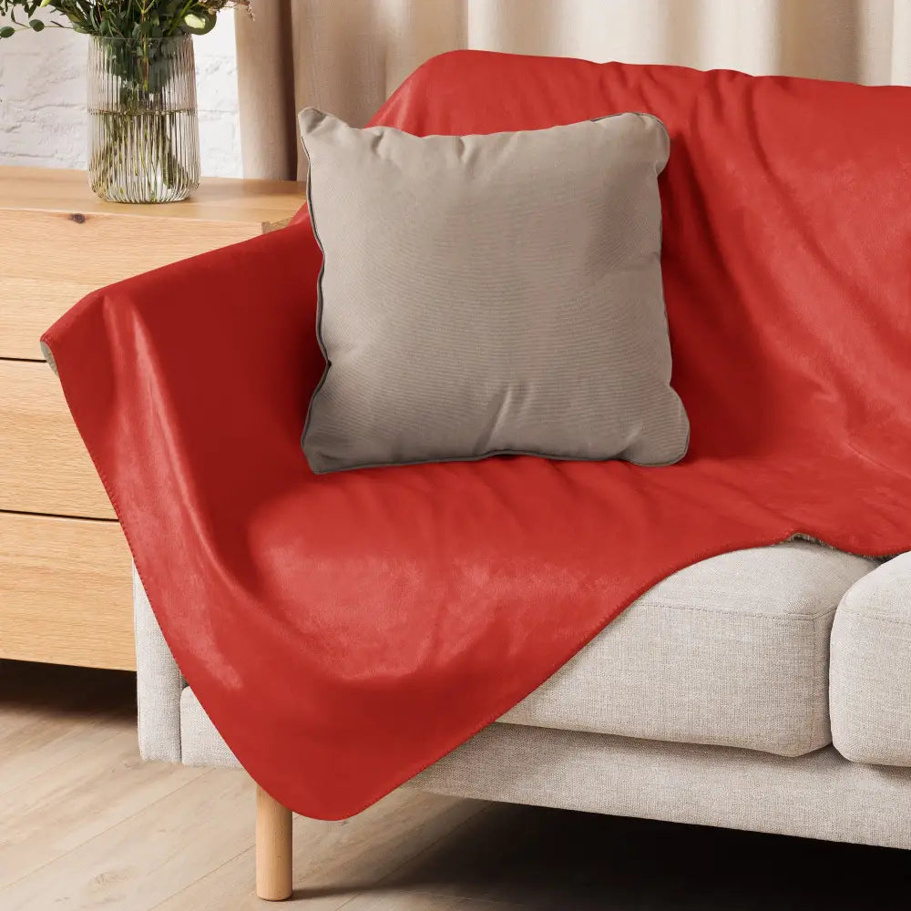 Red sherpa blanket in red velvet draped over a sofa showcasing its soft plush material and cozy design