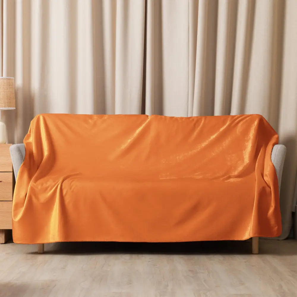 Vibrant orange velvet sherpa blanket elegantly draped over a modern gray armchair for cozy comfort