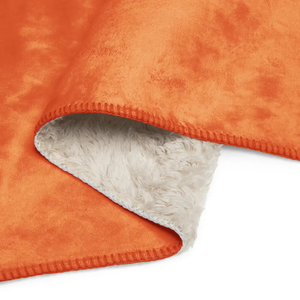 Orange sherpa blanket with soft fluffy white interior lining made of plush material for cozy warmth