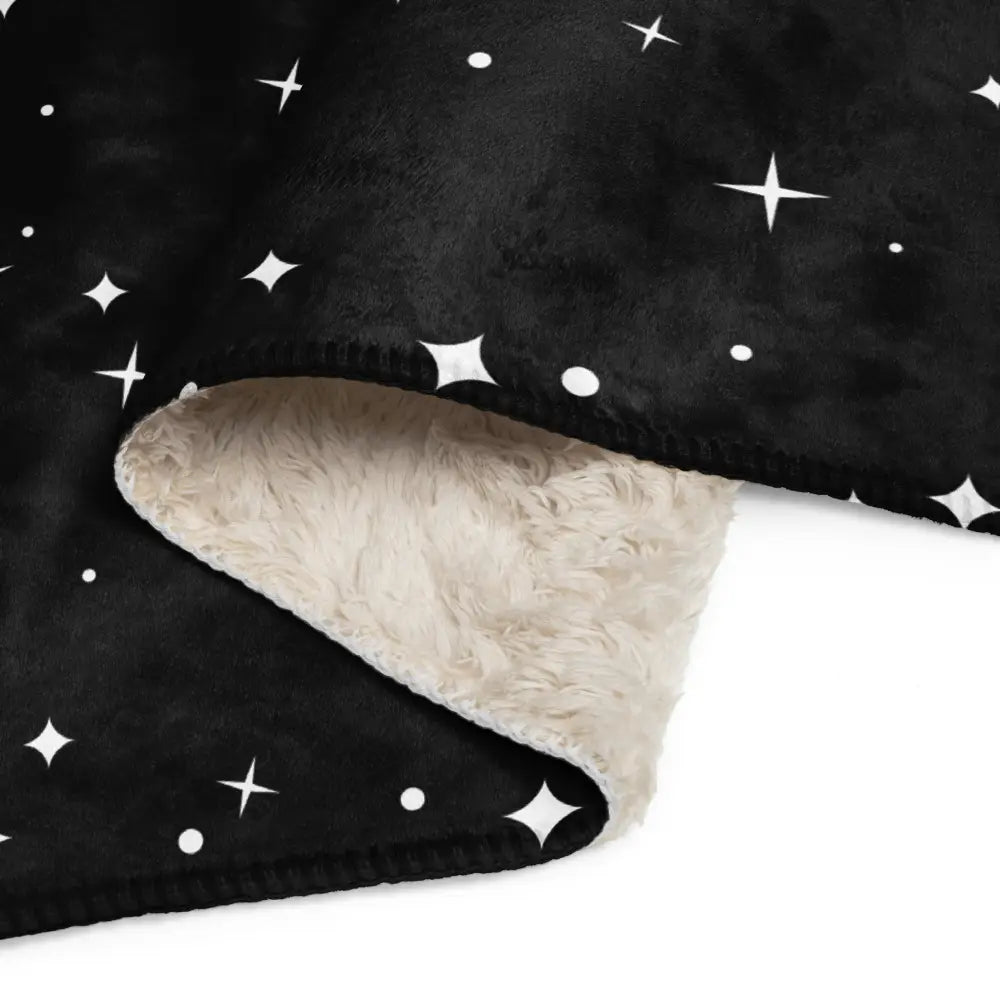 Black plush star sherpa blanket with white star and dot pattern and soft cream-colored sherpa lining