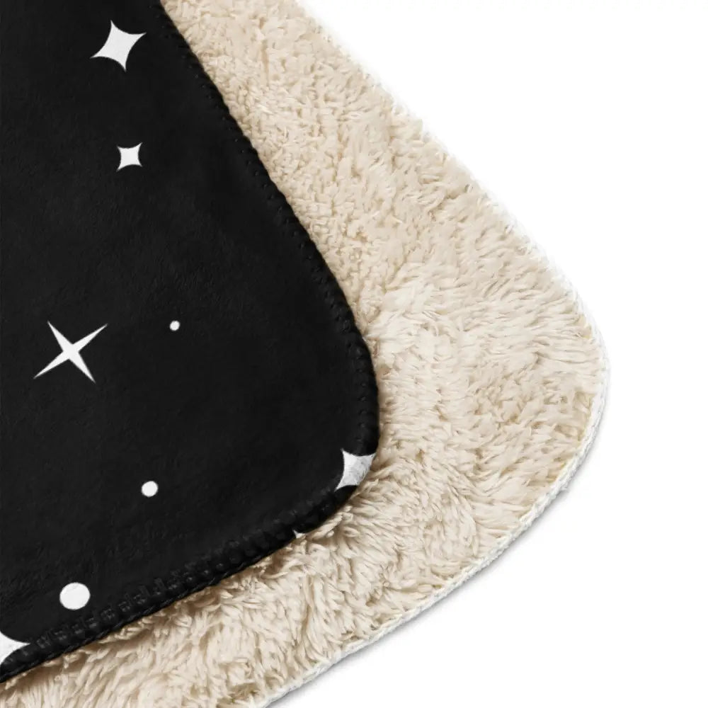 Black fleece star sherpa blanket with white star and dot pattern and plush cream-colored sherpa lining